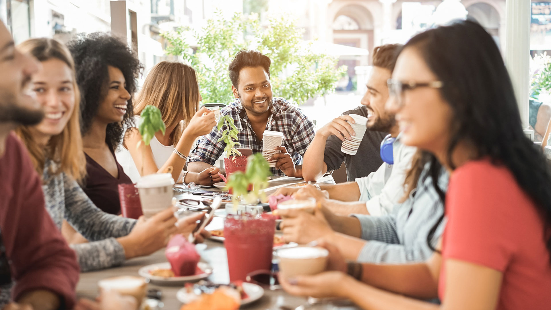 A group of friends sit around a table outside enjoying a brunch.