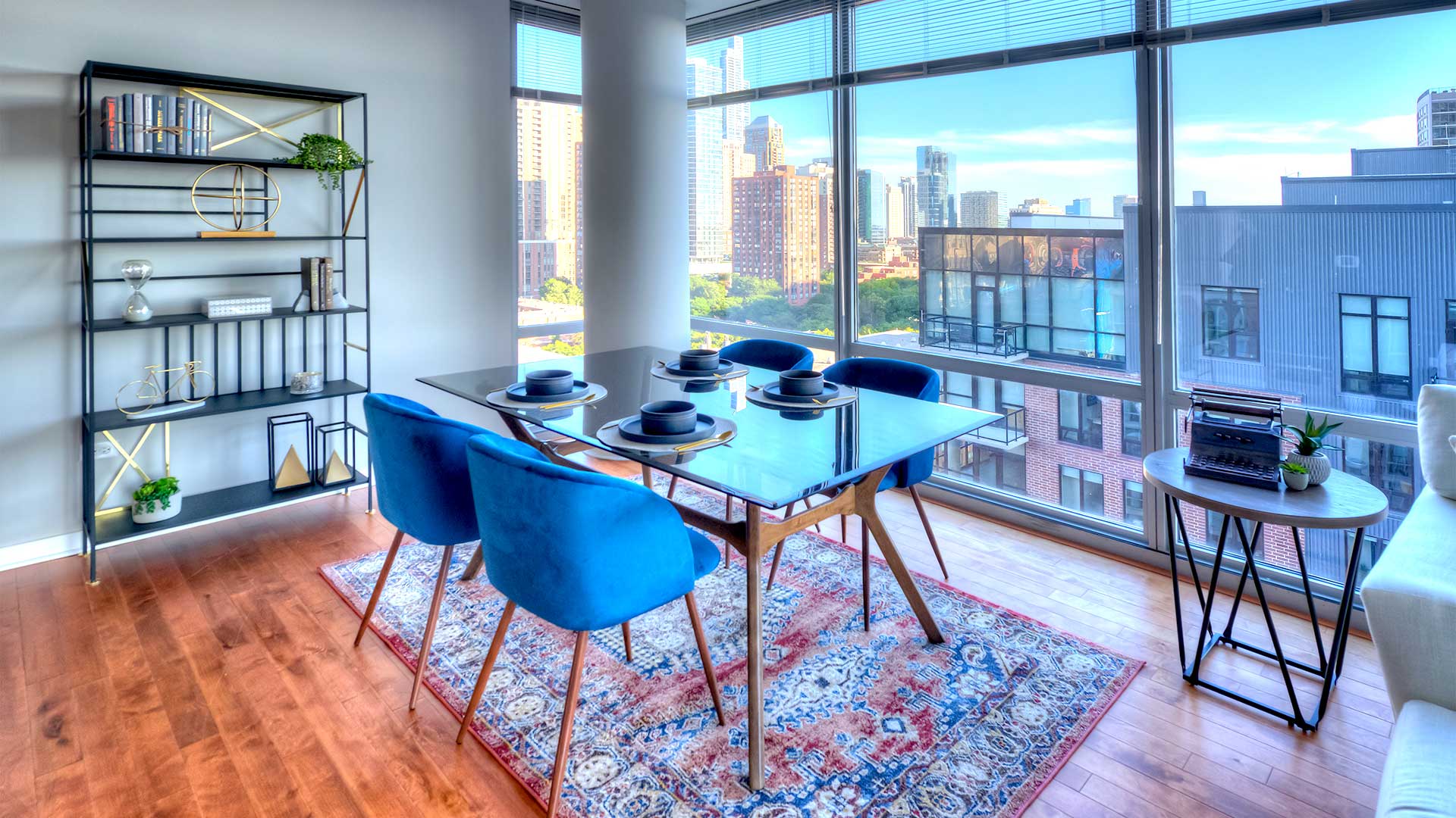 A glass-top dining set sits before floor-to-ceiling windows that show a number of Chicago buildings in the distance.